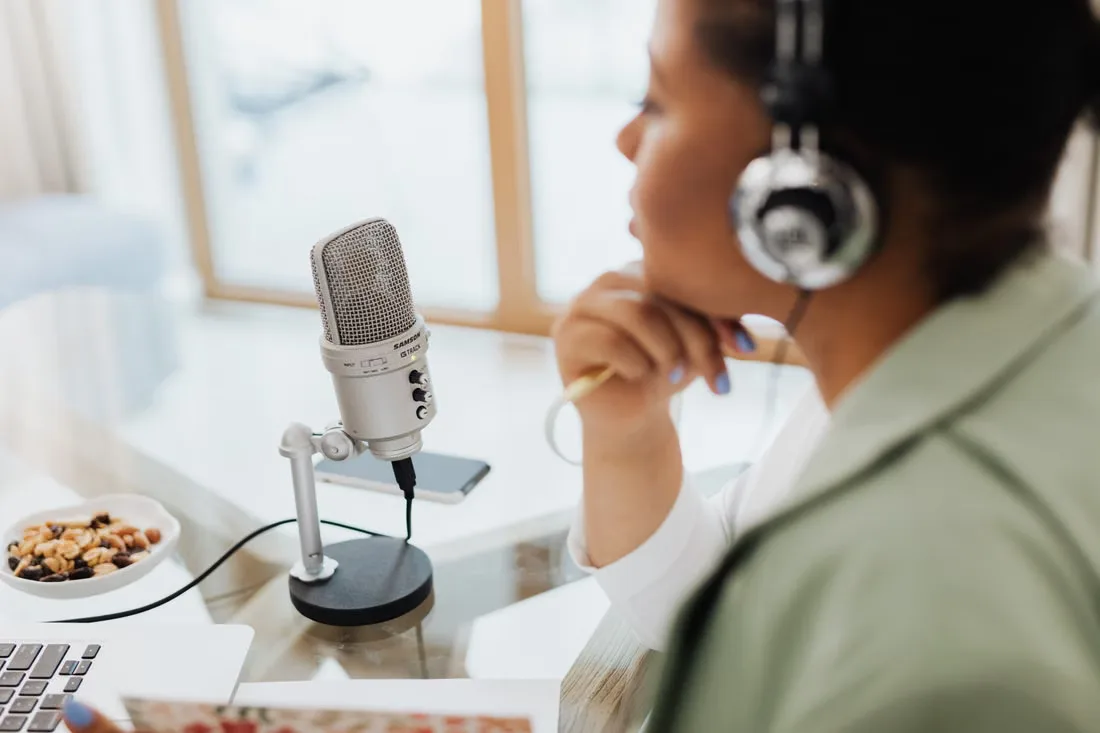 A narrator recording audio at a laptop with a desk microphone